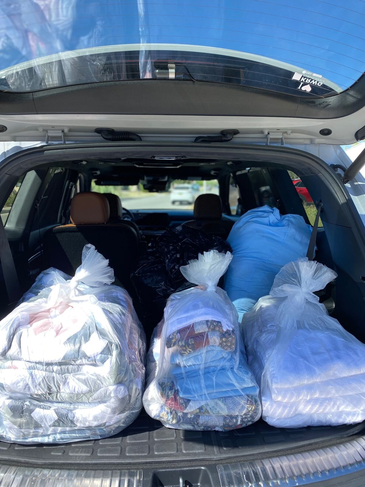 SUV trunk packed with neatly bagged, freshly laundered quilts and bedding ready for delivery